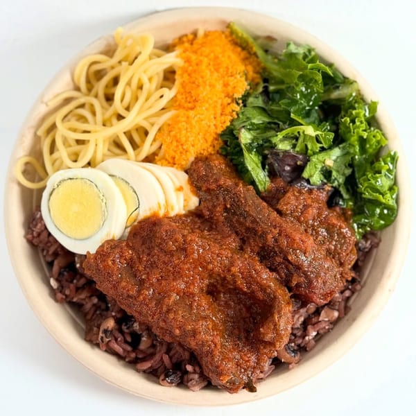 African dish with red rice, meat in red sauce, spaghetti, crumbled topping, kale, and sliced egg.