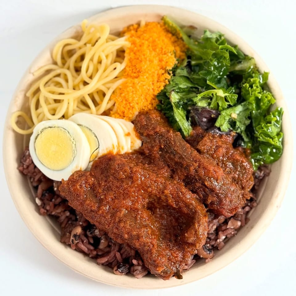 African dish with red rice, meat in red sauce, spaghetti, crumbled topping, kale, and sliced egg.
